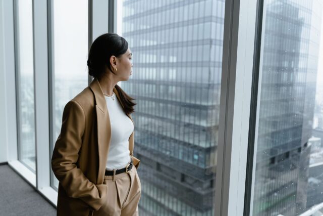 Financial services professional reflecting on work-life balance in a modern office overlooking the city